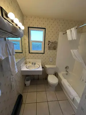a bathroom with a sink and a toilet and a tub at Marina Hotel in Port Alberni