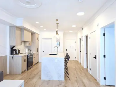 a kitchen with white cabinets and a white counter top at Family Modern 1BR and Den Condo - Apartment with City View, Downtown, Balcony, Free Parking & In-Suite Laundry! in Calgary