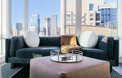 a living room with a blue couch and a coffee table at City View 2 King Suites Floor-to-Ceiling Views in Calgary