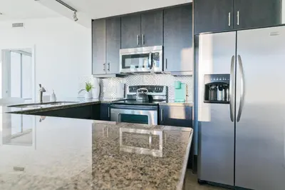 a kitchen with a stainless steel refrigerator and a counter at City View 2 King Suites Floor-to-Ceiling Views in Calgary