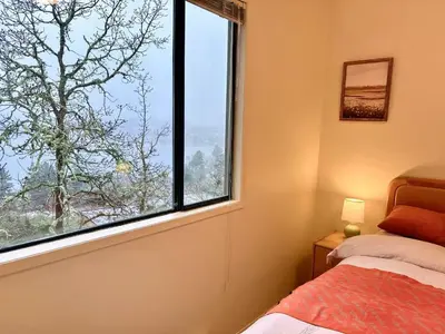 a bedroom with a bed and a large window at Departure view in Nanaimo