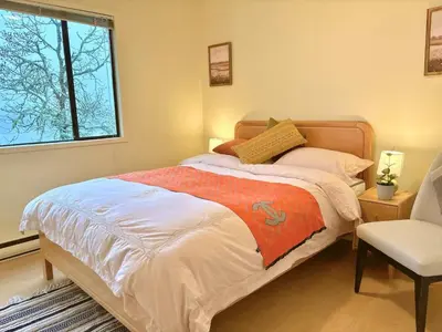 a bedroom with a bed and a chair and a window at Departure view in Nanaimo
