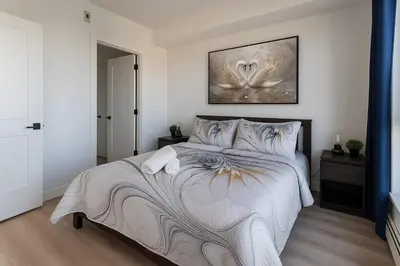 a bedroom with a large bed with a painting on the wall at Family Stylish 1BR and Den Condo -Apartment with City View, Downtown, Balcony, Free Parking, In-Suite Laundry! in Calgary