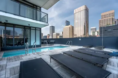 a pool on the roof of a building with a city skyline at Vibrant PopArt downtown suite, comfy and stylish! in Calgary