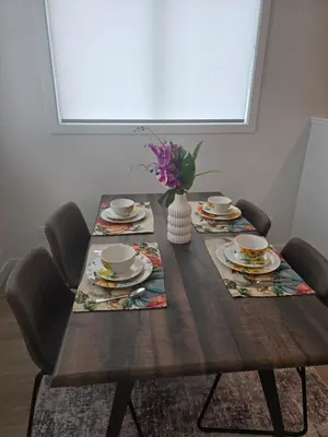 a wooden table with chairs and a vase of flowers at IELS Homes in Edmonton