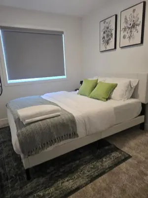 a bedroom with a large bed with green pillows at IELS Homes in Edmonton