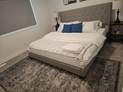 a bedroom with a large bed with blue pillows at IELS Homes in Edmonton