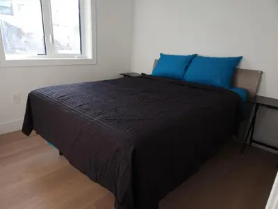 a bedroom with a bed with blue pillows and a window at Urban Elegance: Spacious 2-Bed Townhouse with Modern Charm in Vancouver
