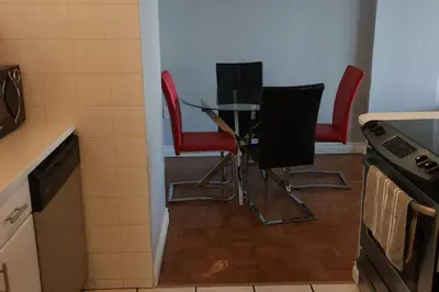 a kitchen with a glass table and red chairs at Elevated Living: 2-Bedroom Upper Apartment in Calgary