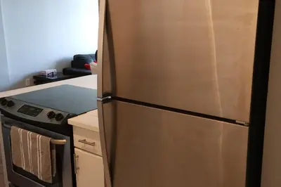 a stainless steel refrigerator in a kitchen next to a stove at Elevated Living: 2-Bedroom Upper Apartment in Calgary