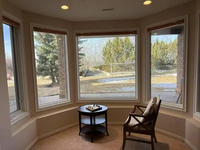 a room with three windows and a table and chairs at Spacious mountain view guesthouse in Calgary