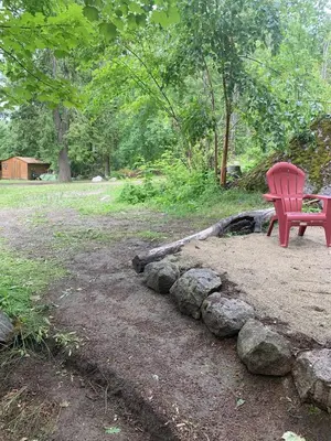a red bench sitting next to a pile of rocks at Cozy and rustic cabin in Nelson