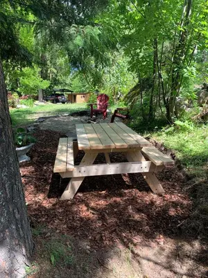 a wooden picnic table with a bench in a park at Cozy and rustic cabin in Nelson