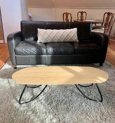 a black leather couch with a wooden coffee table at Cozy and rustic cabin in Nelson