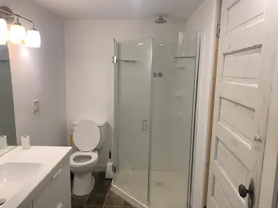 a bathroom with a toilet and a glass shower at Cozy and rustic cabin in Nelson