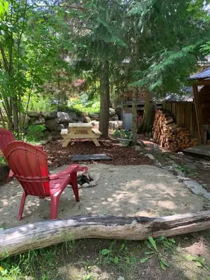 a red chair and a picnic table in a yard at Cozy and rustic cabin in Nelson