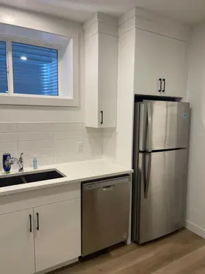 a kitchen with white cabinets and a stainless steel refrigerator at Westminister Manor in Calgary