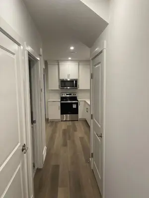 a kitchen with white cabinets and an open door at Westminister Manor in Calgary