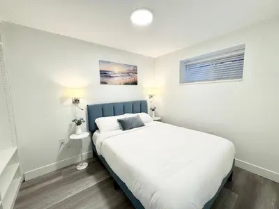 a bedroom with a large white bed with a blue headboard at Perfect Vancouver Travel Hub for Couples or Family in Vancouver