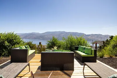 a patio with chairs and tables and a view of the water at Magical Lake View in Peachland