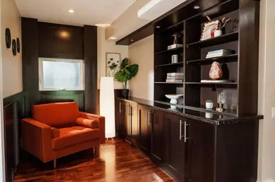 a living room with an orange chair and a counter at 4 Bed Home Along River Near DT AC Hot Tub in Calgary