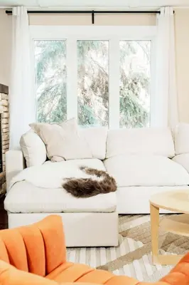 a white couch in a living room with a cat sleeping on it at 4 Bed Home Along River Near DT AC Hot Tub in Calgary
