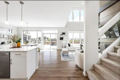 a kitchen and living room with white walls and a staircase at Magnificent Stylish Escape in Bélanger