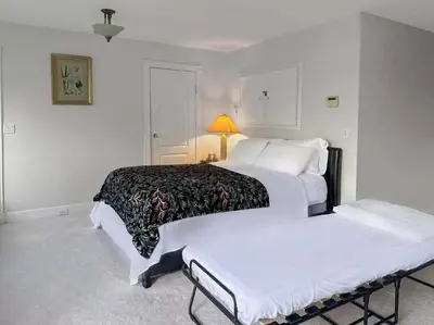 a white bedroom with two beds and a lamp at Garden Suite near Jericho Beach in Vancouver