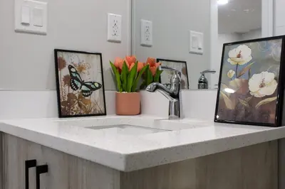a kitchen counter with a sink and two pictures at Cozy 2-Bedroom Walkout Basement Suite in Calgary