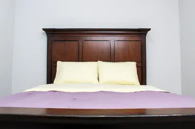 a bed with a wooden head board and two pillows at Cozy 2-Bedroom Walkout Basement Suite in Calgary