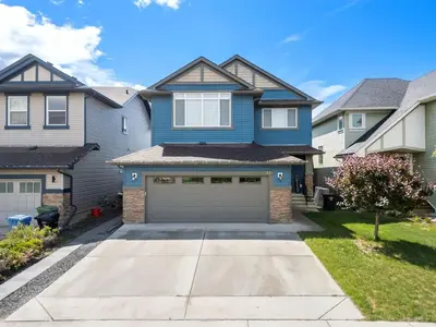 a blue house with a garage in a yard at Meadowstone Suite 3BD 3 TVs Near Spruce Meadows in Calgary