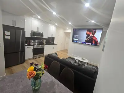 a living room with a couch and a tv on a wall at Cozy 2-Bedroom Basement Suite Just Minutes from the Airport in Calgary