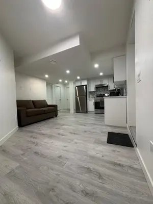an empty living room with a couch and a kitchen at 2 bedroom Basement Suite in Calgary