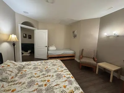 a bedroom with a bed and a chair and a door at Relaxing Lakeview 2 bedroom entire suite in Kelowna