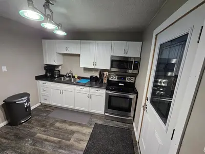 a kitchen with white cabinets and a stove top oven at Cozy Bungalow
