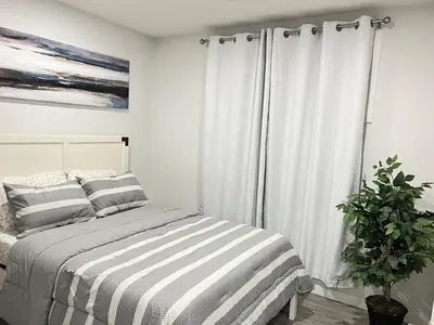 a bedroom with a striped bed and a plant at 1-BR Suite with Private entrance near Restaurants, Shops, Local Amenities in Edmonton