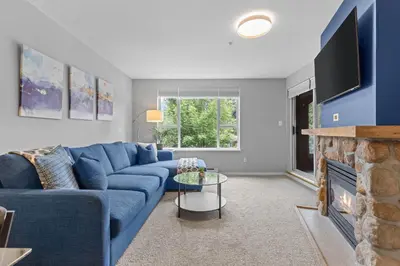 a blue couch in a living room with a fireplace at 2BR in Deer Lodge, Epic Location, Private Covered Patio, Free Parking in Whistler