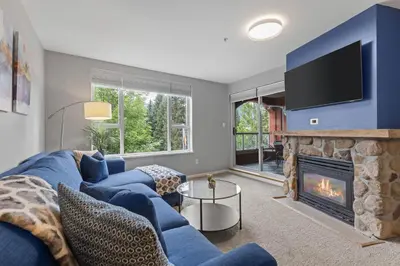 a living room with a blue couch and a fireplace at 2BR in Deer Lodge, Epic Location, Private Covered Patio, Free Parking in Whistler