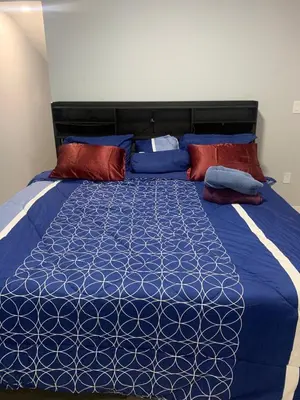 a bedroom with a blue bed with red and blue pillows at Modern 1BR Entire Suite Near Airport in Calgary