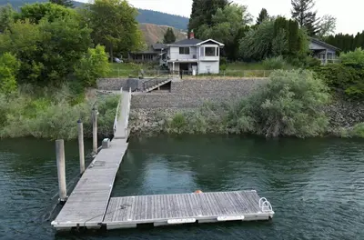 a dock on a river with a house in the background at Private Bedroom at Riverfront House in Kamloops