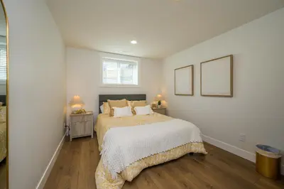 a white bedroom with a bed and two lamps at Forest Haven on the Ridge in Prince George