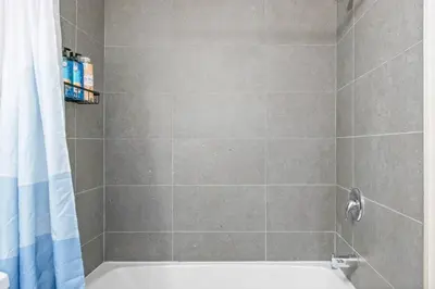 a shower with a white tub and a shower curtain at Elegant Living in a 1-Bedroom Suite in Edmonton