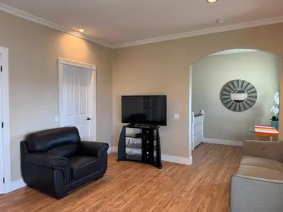a living room with a chair and a television at SHARED Lakeview Peaceful 2BR Stay in Beautiful Kelowna in Kelowna