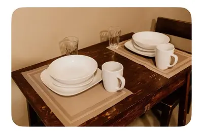 a wooden table with two plates and cups on it at Lower suite in family friendly townhome in Victoria
