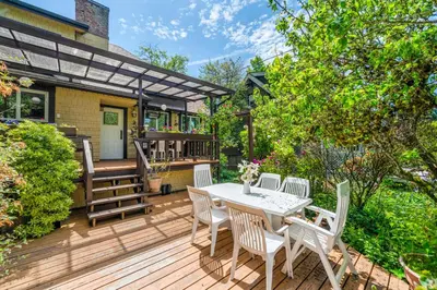 a wooden deck with a table and chairs at Picturesque room surrounded by flowers with share spaces in Vancouver