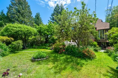 a yard with a house and trees and bushes at Picturesque room surrounded by flowers with share spaces in Vancouver