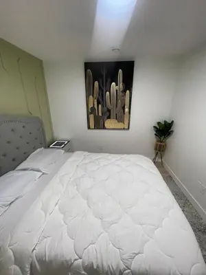 a bedroom with a white bed with a painting on the wall at Shiloh Residence in Edmonton
