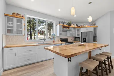 a kitchen with white cabinets and a wooden counter top at 4-bedroom with Game Room & Hot Tub in Fernie