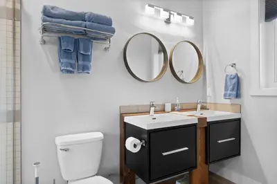 a bathroom with a toilet and a sink and mirrors at 4-bedroom with Game Room & Hot Tub in Fernie