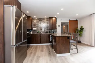 a kitchen with a stainless steel refrigerator and wooden cabinets at Cozy 1-Bedroom Retreat in the Heart of Langford in Victoria